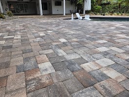 Patterned paver driveway with geometric design in front of modern house with garage and pillars