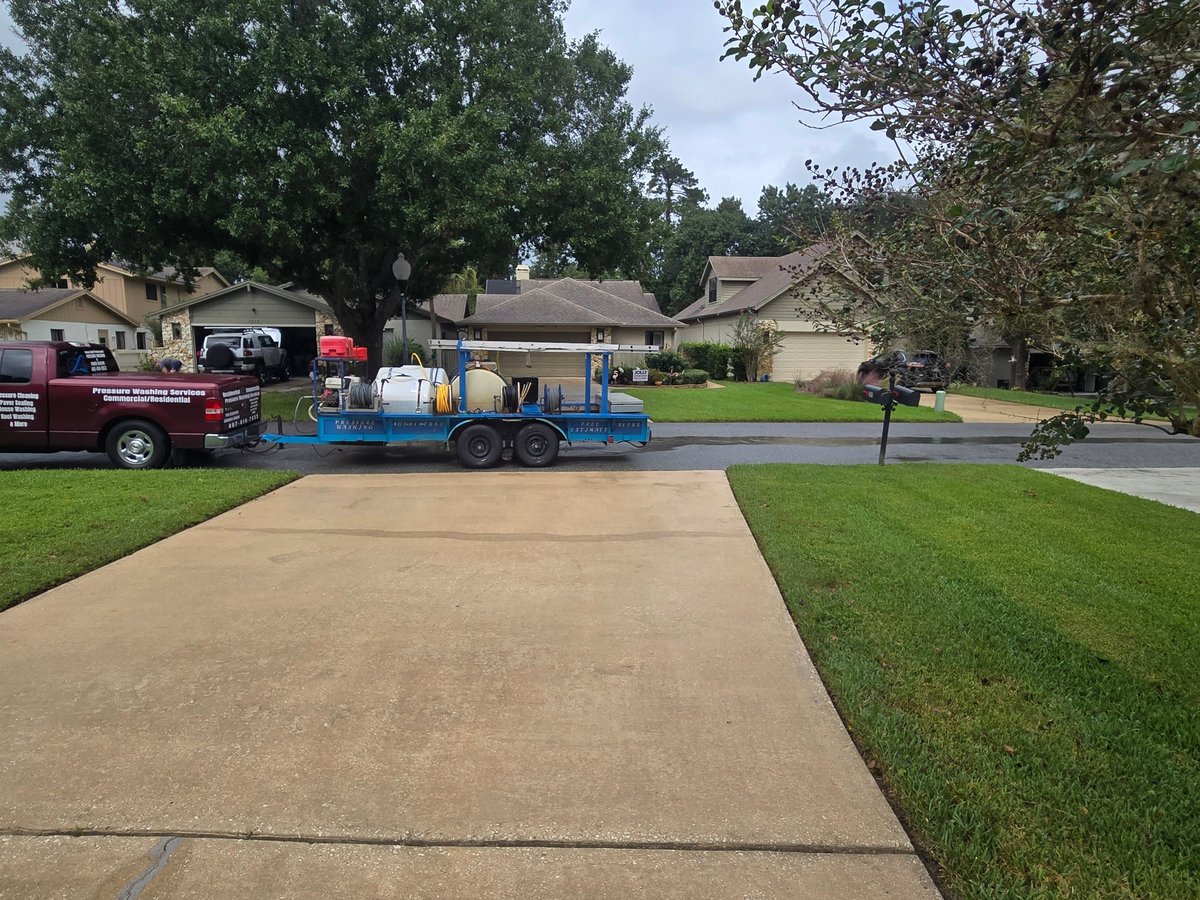Blue tanker trailer parked on a residential street beside a clean concrete driveway
