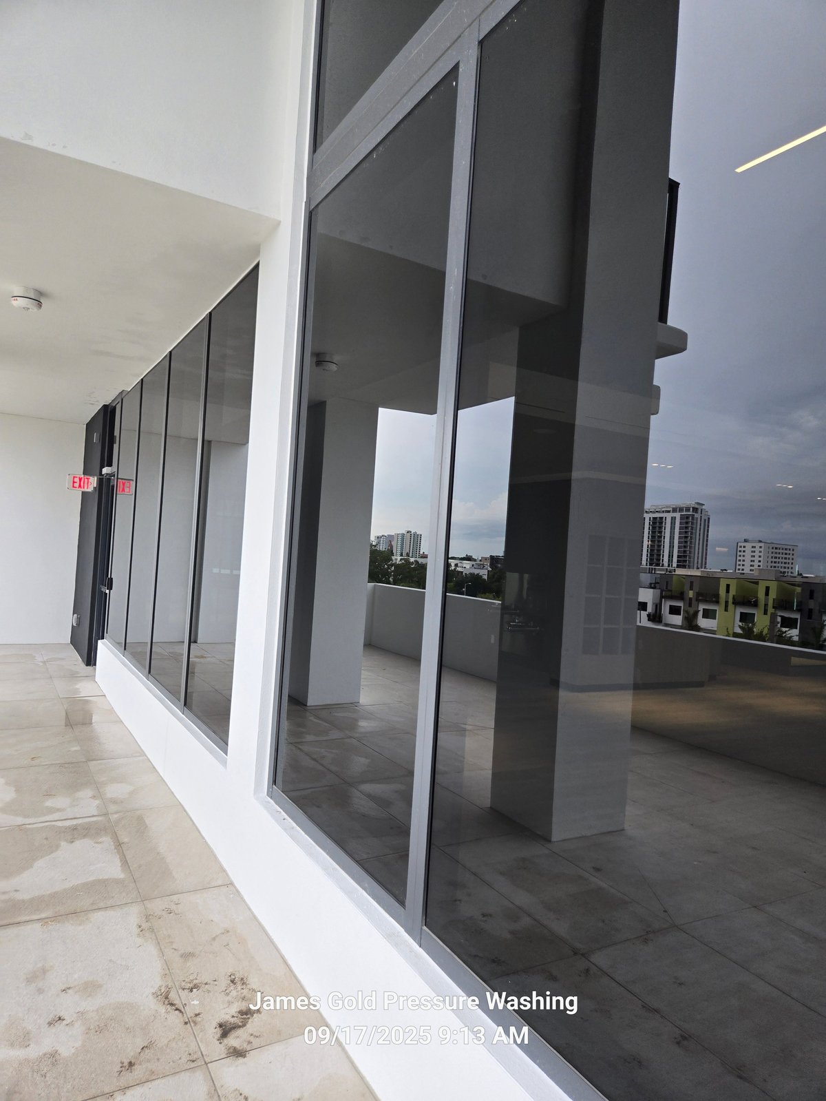 Modern rooftop patio with black-framed glass sliding doors and city skyline view in background