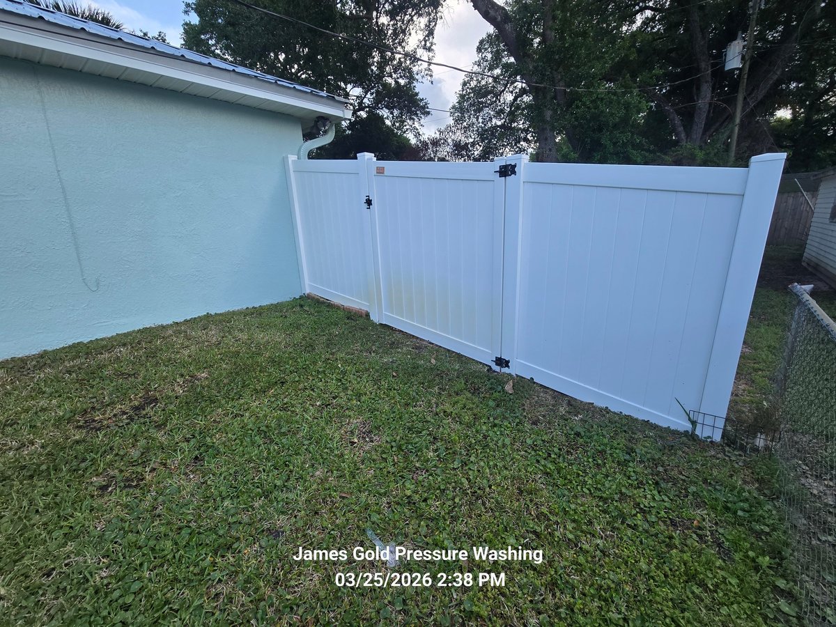 White vinyl fence gate installed in a backyard with green grass and house in background