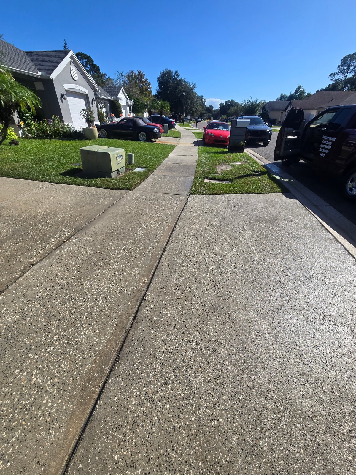 Clean concrete driveway leading to a white house on a suburban street