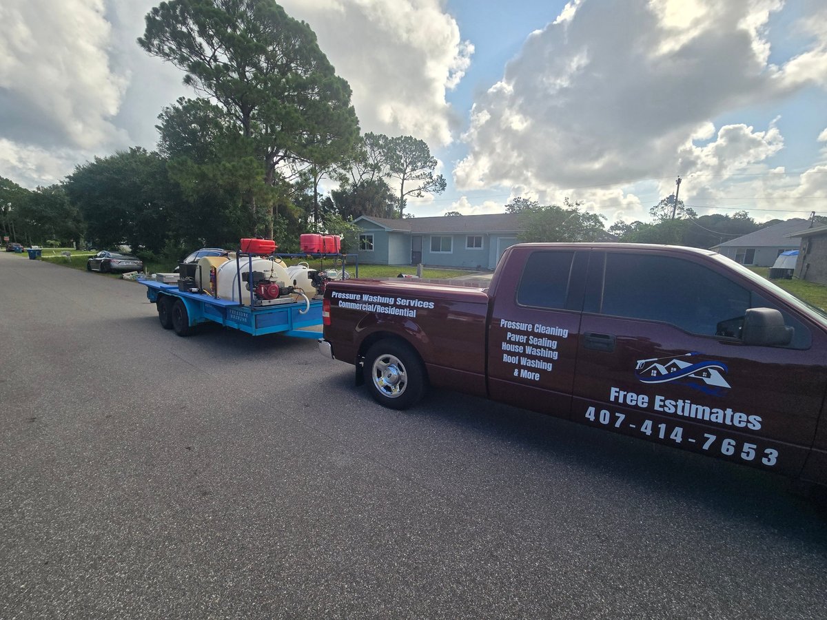 Two service vehicles parked in a lot: a blue and red pickup truck and a maroon van with business contact information and free estimates offer displayed