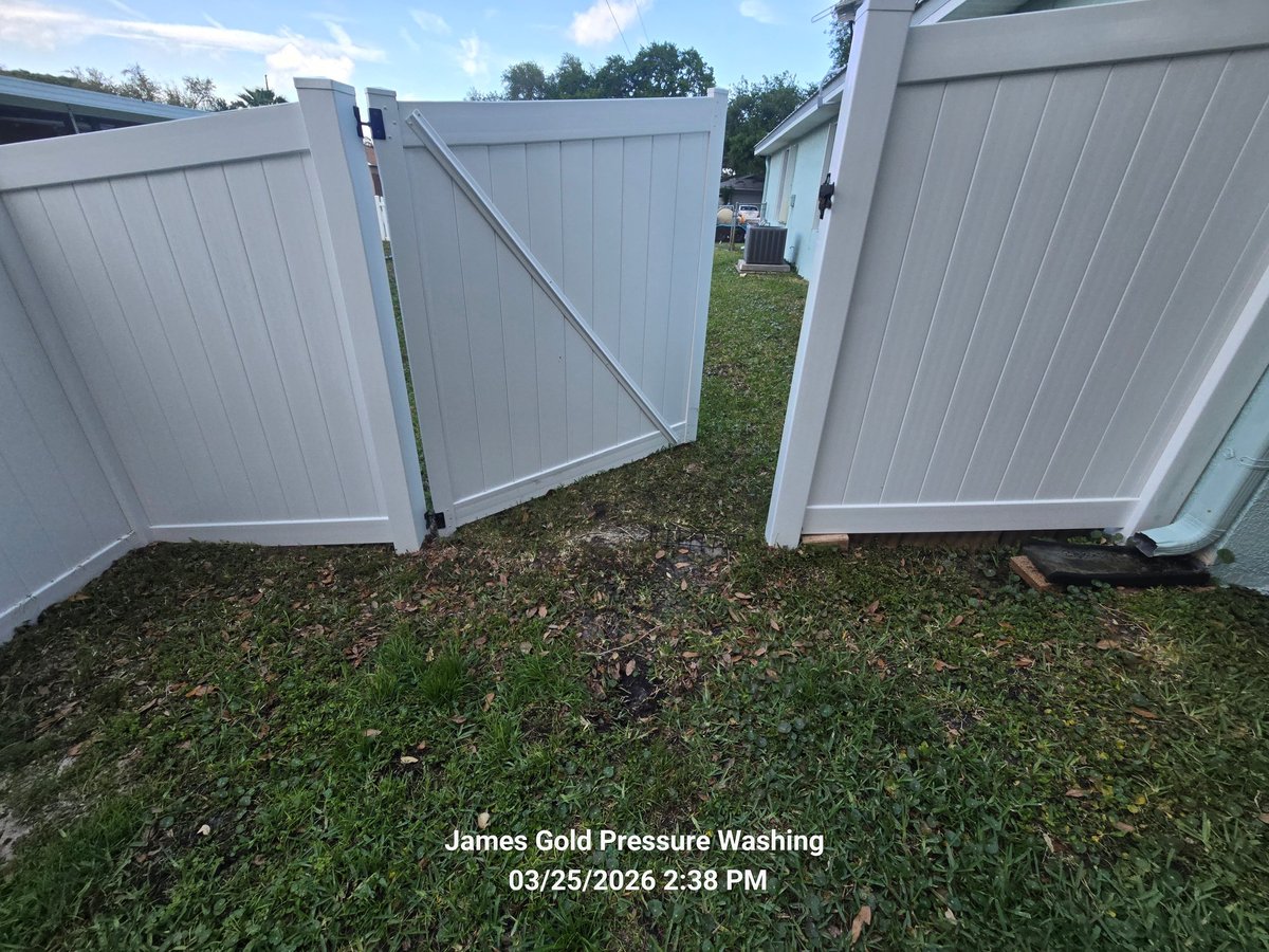 Two clean white vinyl fence panels standing on grass with trees in the background